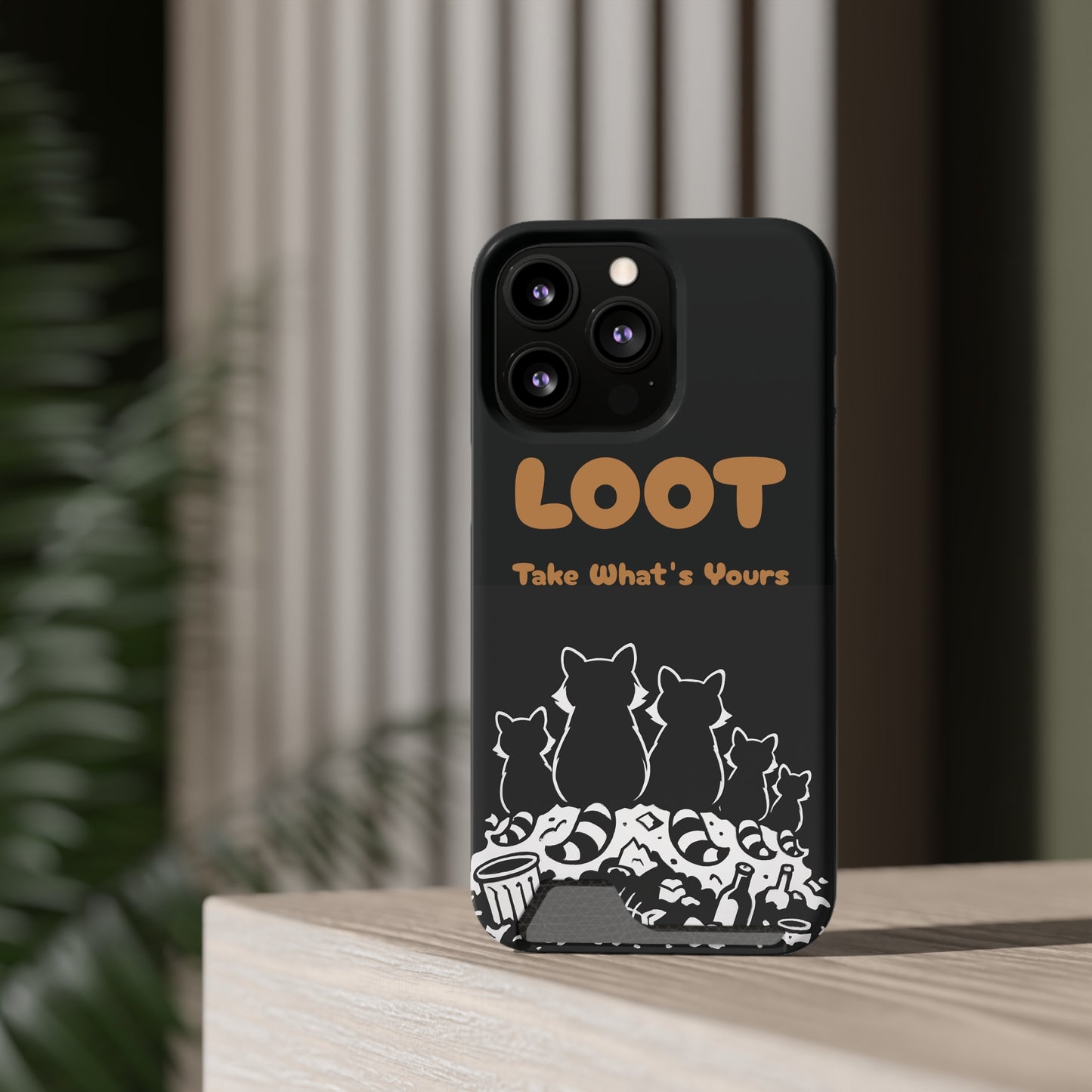 Phone case with 'LOOT' text and raccoon illustrations on a wooden surface, back