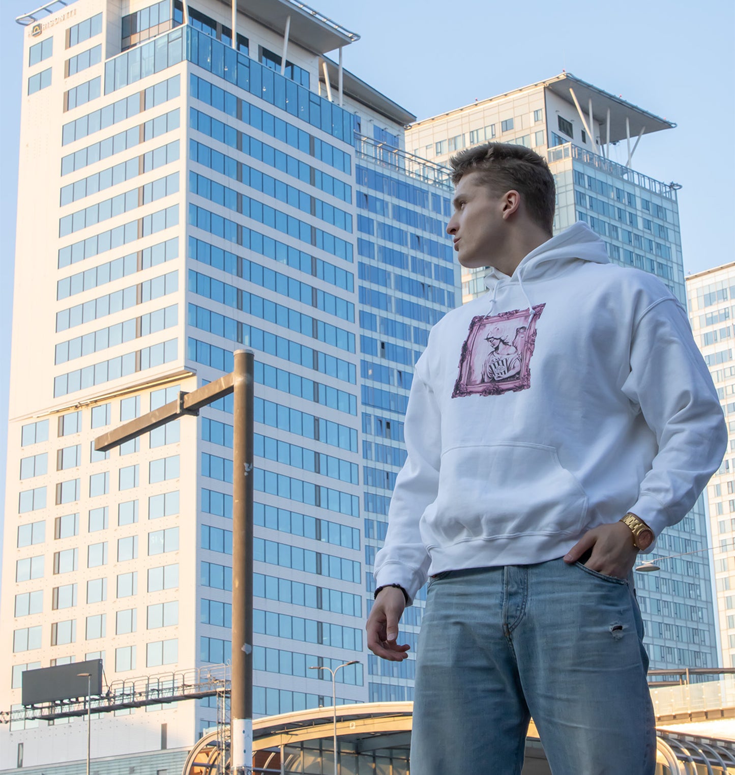Person wearing a white hoodie with a graphic design in an urban setting, front